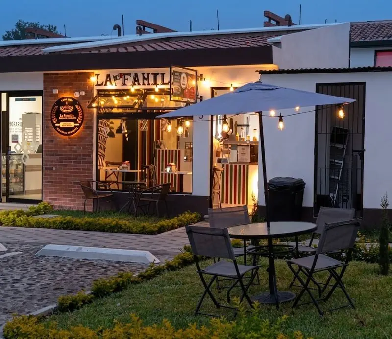 Fachada de La Familia al atardecer con mesas en el jardín