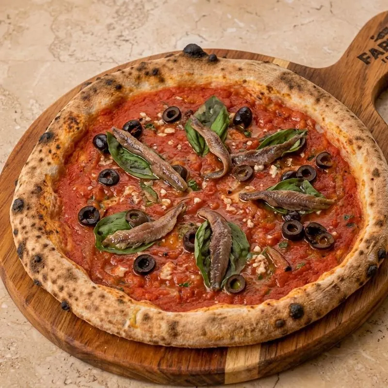 Pizza de anchoas con aceitunas negras y albahaca
