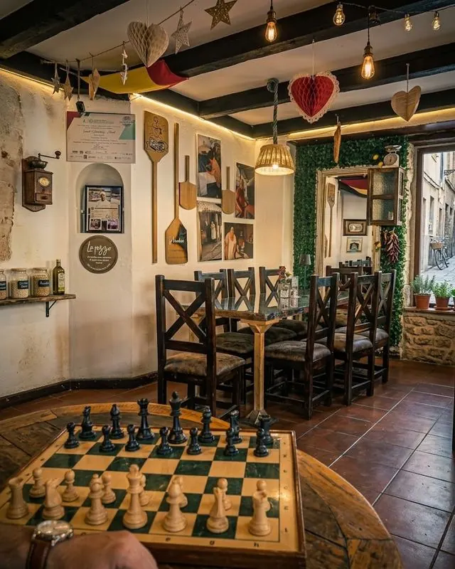 Rincón con tablero de ajedrez, palas de pizza decorativas y mesas de madera